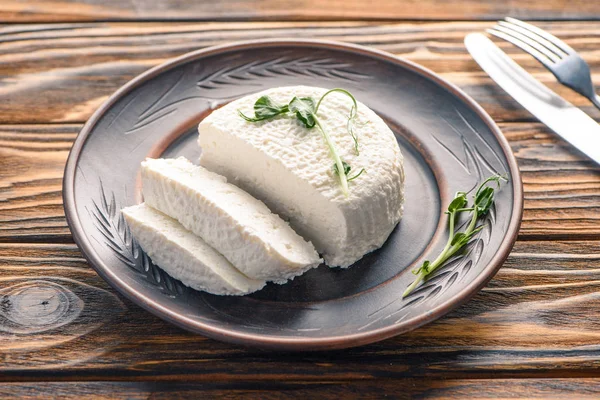 Крупный план вкусного здорового мягкого сыра на тарелке на деревянном столе — стоковое фото
