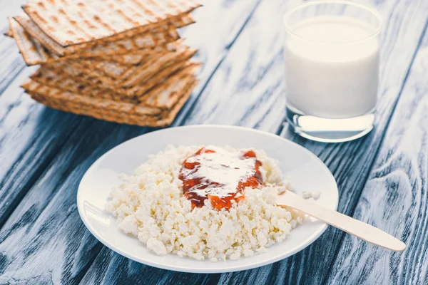 Primer plano vista de requesón con mermelada en plato, vaso si leche y galletas en mesa de madera - foto de stock