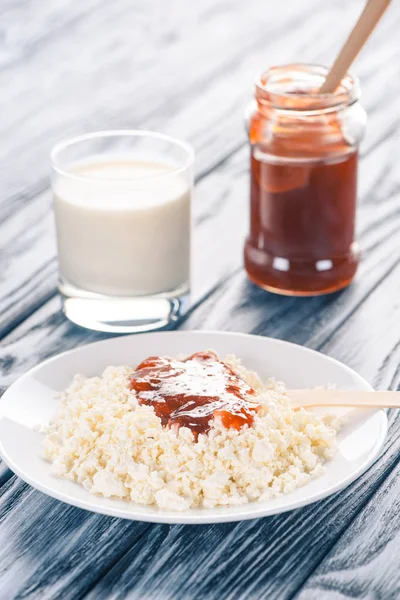 Close-up view of delicious cottage cheese with jam and glass of milk on wooden table — Stock Photo