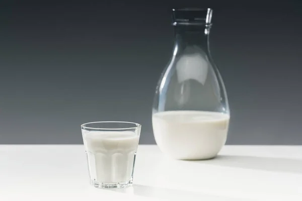 Milch in Glas und Flasche auf Tisch auf grauem Hintergrund — Stockfoto