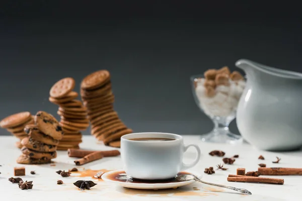 Tasse mit verschüttetem Kaffee auf dem Tisch mit Keksen und Gewürzen — Stockfoto