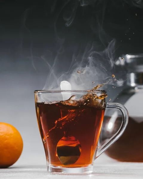 Смешивание черного чая с ложкой в стеклянной чашке — стоковое фото