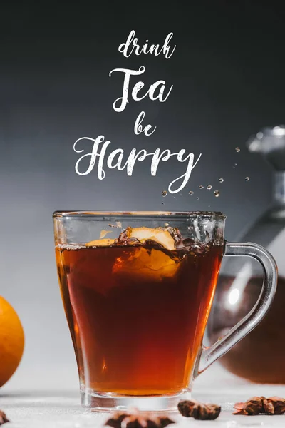 Piezas de limón salpicando en taza con beber té y ser feliz inscripción - foto de stock