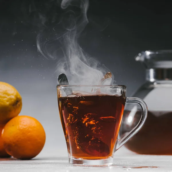 Spoon in glass cup with steaming black tea — Stock Photo