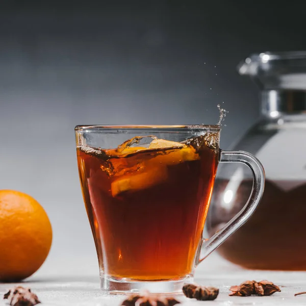 Morceaux d'agrumes éclaboussant dans une tasse de thé noir épicé — Photo de stock