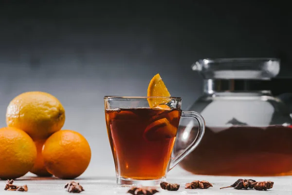 Hot black tea in cup with lemons and oranges — Stock Photo