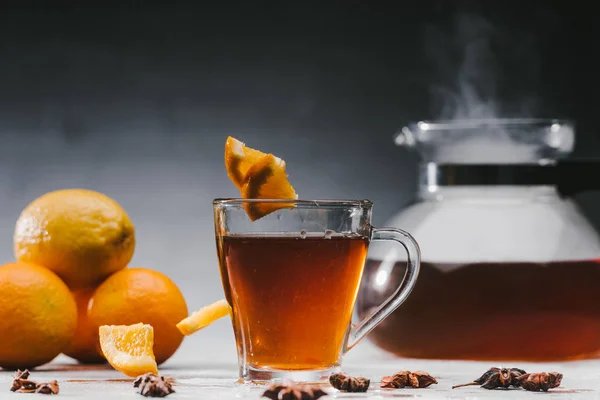 Tè nero in tazza con limoni e anice stellato in tavola — Foto stock