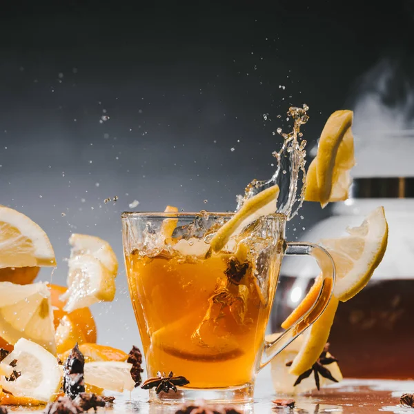 Glas heißer, dampfender Tee mit spritzenden Zitrusfrüchten — Stockfoto