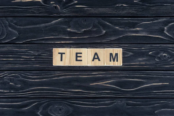 Ansicht von Wort-Team aus Holzklötzen auf dunkler Holztischplatte — Stockfoto