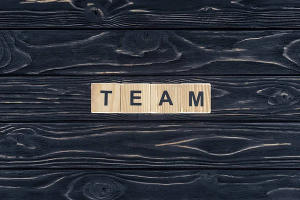 Top view of word team made of wooden blocks on dark wooden tabletop — Stock Photo