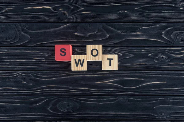 Vista superior da palavra swot feito de blocos de madeira em mesa de madeira escura — Fotografia de Stock