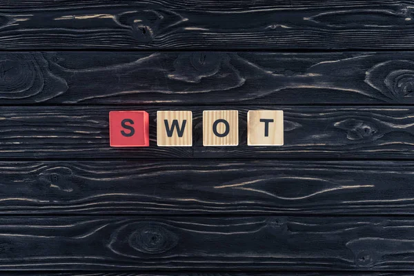 Vista superior da palavra swot feito de blocos de madeira em mesa de madeira escura — Fotografia de Stock
