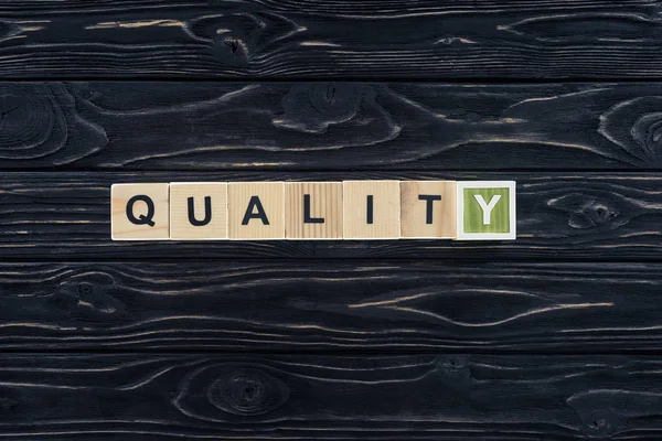 Top view of word quality made of wooden blocks on dark wooden tabletop — Stock Photo