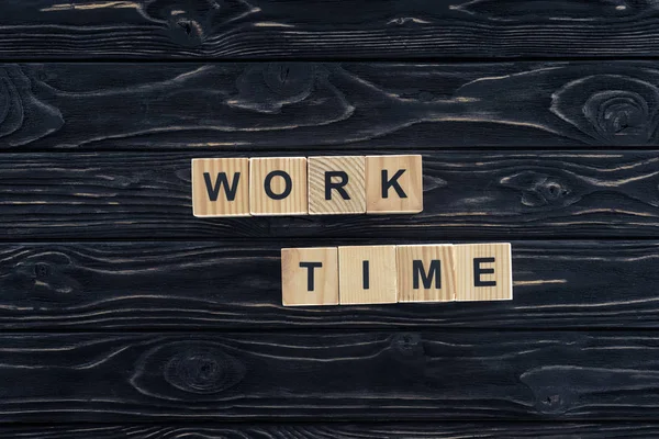 Вид зверху на робочий час слова з дерев'яних блоків на темній дерев'яній стільниці — стокове фото