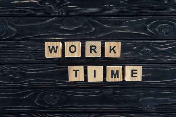 Top view of work time words made of wooden blocks on dark wooden tabletop — Stock Photo