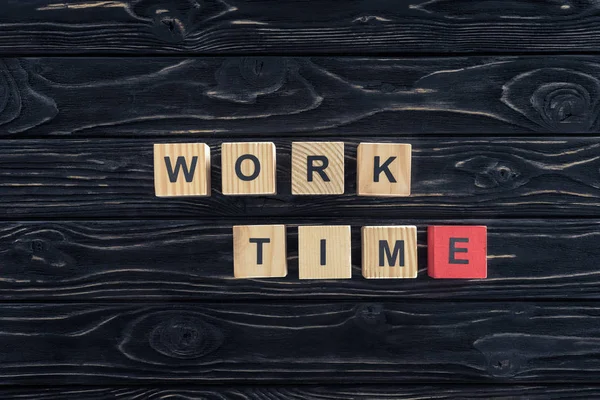 Top view of work time words made of wooden blocks on dark wooden tabletop — Stock Photo