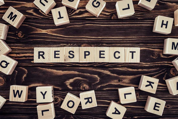 Flat lay with arranged wooden blocks in respect word on brown wooden surface — Stock Photo