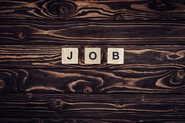 Top view of wooden blocks arranged in job word on brown wooden tabletop — Stock Photo