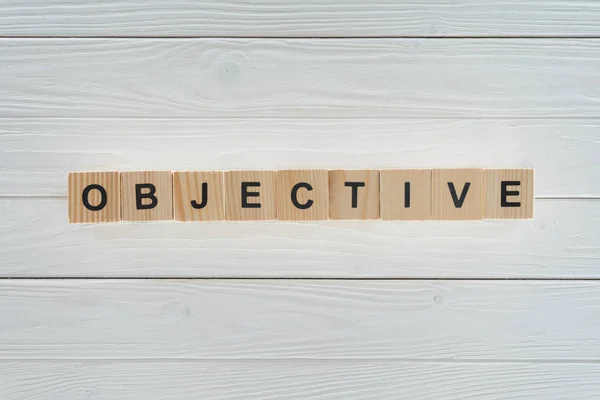Vista superior de palabra objetiva hecha de bloques en superficie de madera blanca - foto de stock