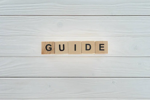 Top view of guide word made of wooden blocks on white wooden surface — Stock Photo