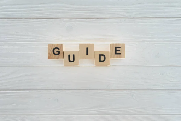 Vue du dessus du mot guide fait de blocs de bois sur une surface en bois blanc — Photo de stock