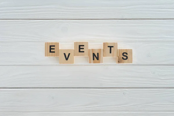 Vista superior de eventos palabra hecha de bloques de madera en la superficie de madera blanca - foto de stock