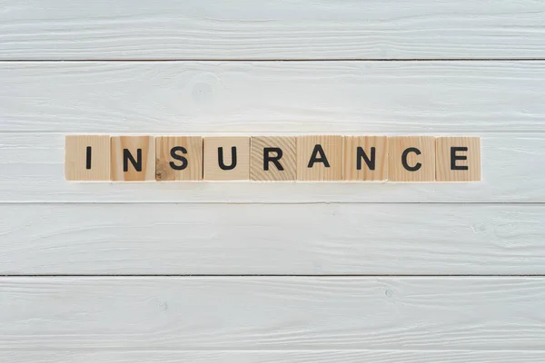 Top view of insurance word made of wooden blocks on white wooden surface — Stock Photo