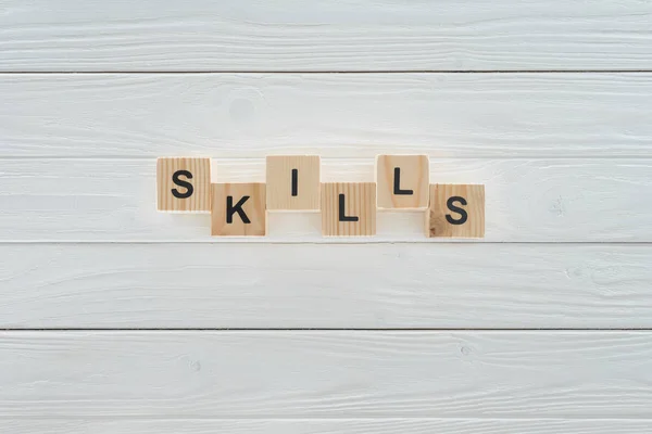 Vue du dessus de l'inscription des compétences en blocs sur une surface en bois blanc — Photo de stock