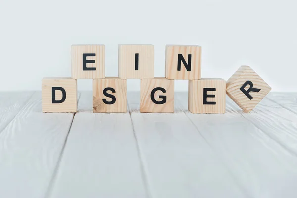 Close up view of designer word made of wooden cubes on white wooden tabletop — Stock Photo