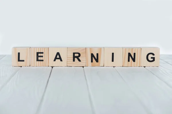 Close up view of learning word made of wooden cubes on white wooden tabletop — Stock Photo