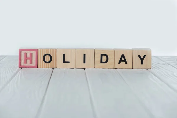 Close up view of holiday word made of wooden cubes on white wooden tabletop — Stock Photo