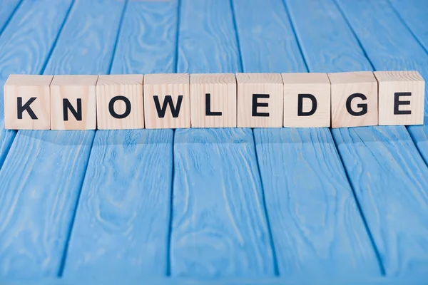 Close up view of knowledge word made of wooden blocks on blue tabletop — Stock Photo