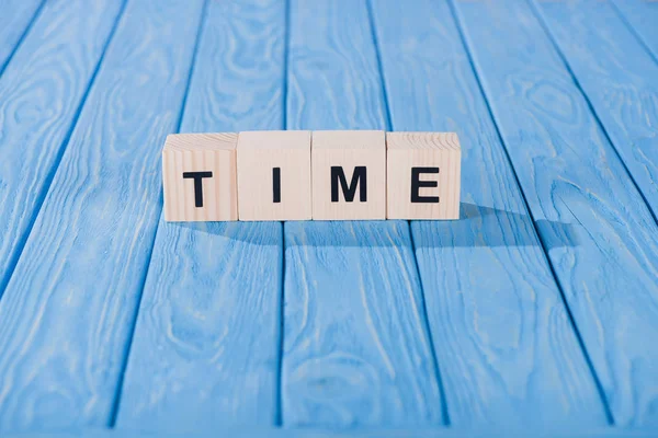 Close up view of time word made of wooden cubes on blue surface — Stock Photo