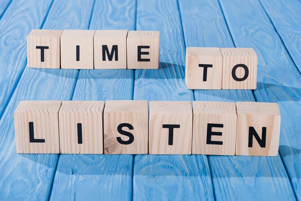 Close up view of arranged wooden blocks into time to listen phrase on blue wooden surface — Stock Photo