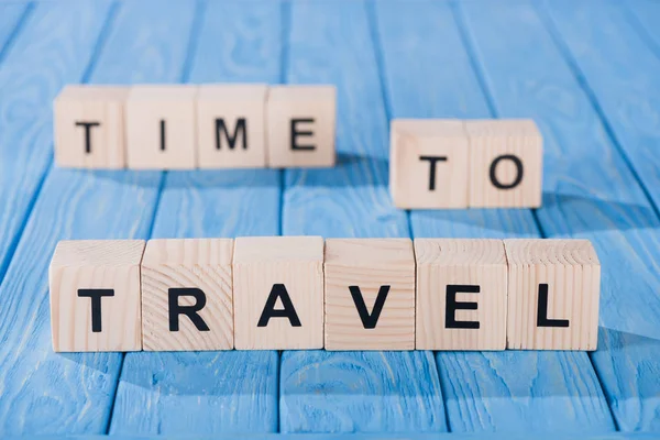 Close up view of arranged wooden blocks into time to travel phrase on blue wooden surface — Stock Photo