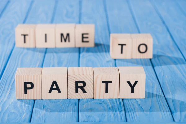 Close up view of arranged wooden blocks into time to party phrase on blue wooden surface — Stock Photo