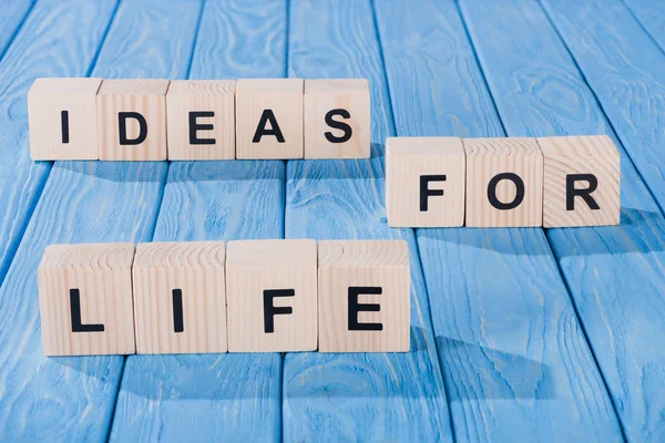 Close up view of arranged wooden blocks into ideas for life phrase on blue wooden surface — Stock Photo