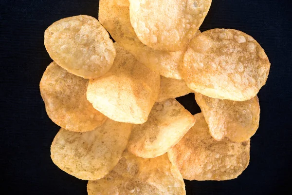 Крупный план хрустящих нездоровых картофельных чипсов, изолированных на черном — стоковое фото