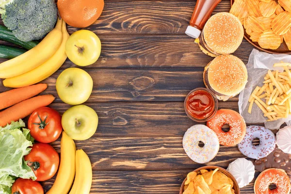 Top view of fresh ripe fruits with vegetables and assorted junk food on wooden table — Stock Photo