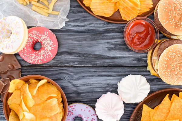 Vista superior de doces variados e junk food na mesa de madeira — Fotografia de Stock