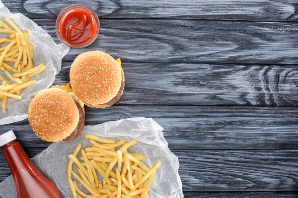 Vue de dessus des hamburgers avec frites et ketchup sur table en bois — Photo de stock