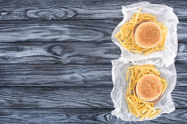 Top view of two hamburgers with french fries on wooden table — Stock Photo