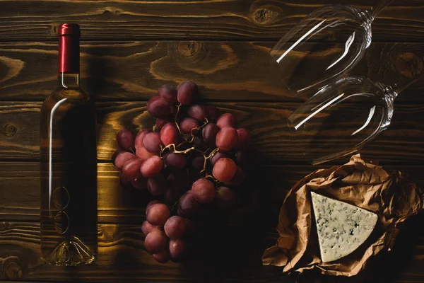 Vue du dessus de la bouteille de vin blanc avec des entrées et des verres à vin sur une table en bois — Photo de stock