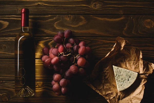 Draufsicht auf eine Flasche Weißwein mit Häppchen auf einem Holztisch — Stockfoto