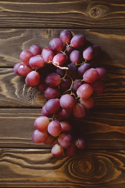 Top view of branch of ripe red grapes on wooden table — Stock Photo