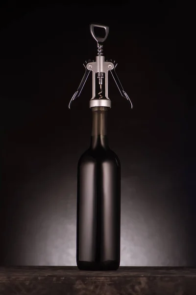 Bottle of luxury red wine pierced with corkscrew on black — Stock Photo