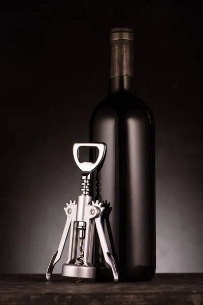 Bottle of delicious red wine with corkscrew on black — Stock Photo