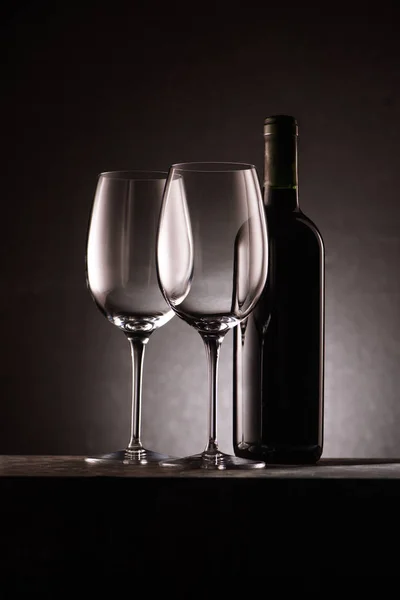 Bottle of wine with two empty glasses on black — Stock Photo