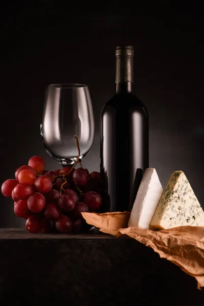 Delizioso vino rosso con uva e formaggio su nero — Foto stock