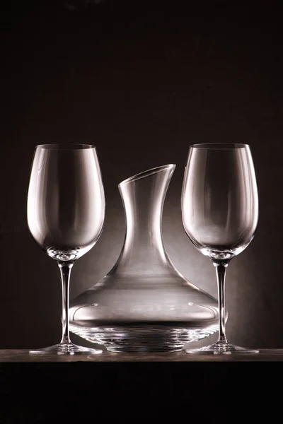 Carafe vide entre deux verres à vin sur noir — Photo de stock